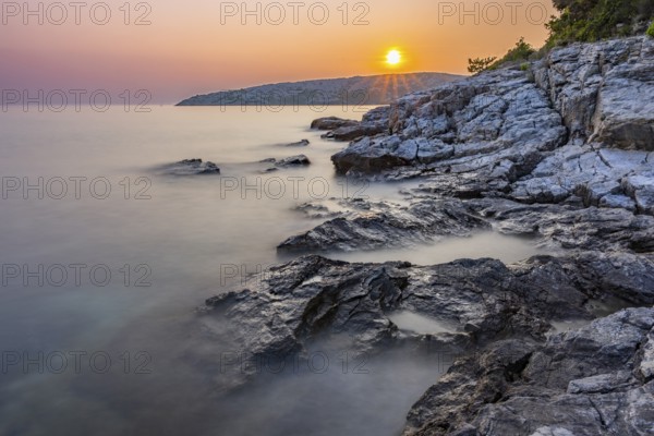 Sunset over crystal clear water on the beach of Ustrine Bay on the island of Cres, long exposure,