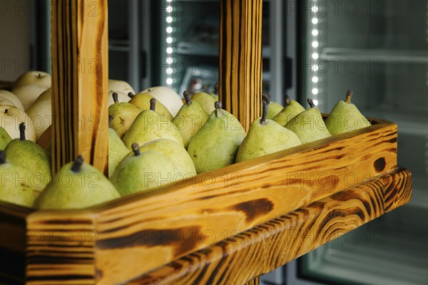 Fresh green pears neatly arranged in a rustic wooden display case at a market in Tulum, Mexico. The