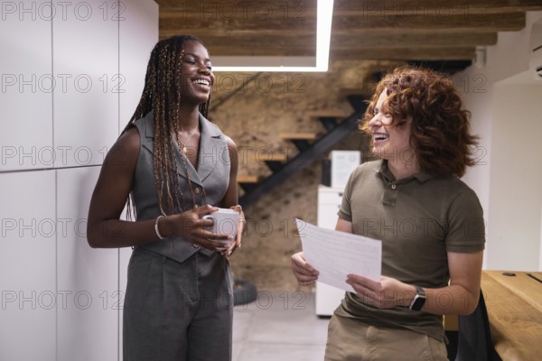 Two coworkers enjoy a lighthearted conversation in a modern office setting, fostering a positive