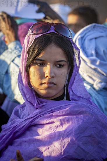 A pensive woman in a purple robe and sunglasses in the evening light, Veiled woman at the