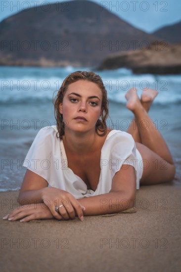 Lifestyle of a blonde Caucasian girl in a white swimsuit. Lying on the sand after getting out of