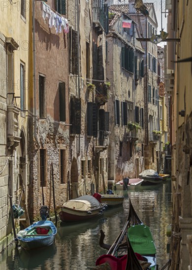 Narrow canal between tall old buildings, lined with boats in a quiet, historic neighbourhood,