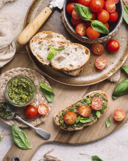 Rustic toasts topped with vibrant cherry tomatoes and fragrant pesto, presented on a wooden board.