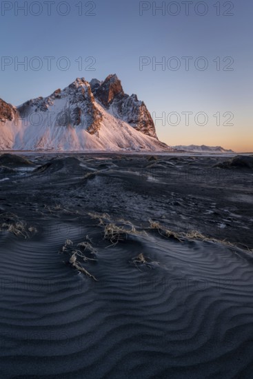 A stunning view of Stokksnes Mountain in Iceland, illuminated by the warm light of sunrise. The