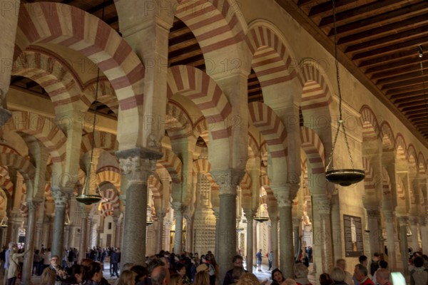 Architecture with striking arches and red and white stripes, interior filled with people, Cathedral