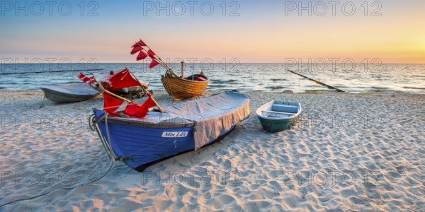 Fishing boats with red flags on fine sandy beach at sunrise, Baltic resort Kölpinsee, Usedom