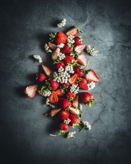A visually striking arrangement of ripe strawberries beautifully scattered on a dark stone surface,