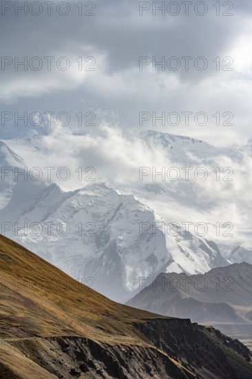 Dramatic mountain landscape, mountain valley, behind glaciated and snow-covered mountain peak Pik