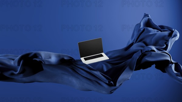 A sleek laptop is placed atop smooth fabric, showcasing its lightweight design against a rich blue
