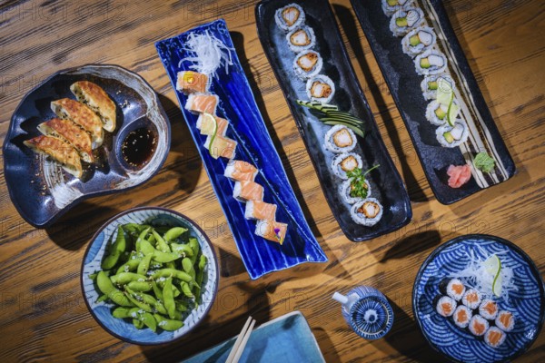 Overhead view of a colorful assortment of japanese cuisine, including sushi rolls, gyoza, edamame,