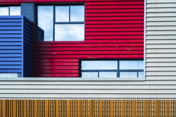 This image captures the vibrant and modern urban facade of a building, featuring a bold mix of red,