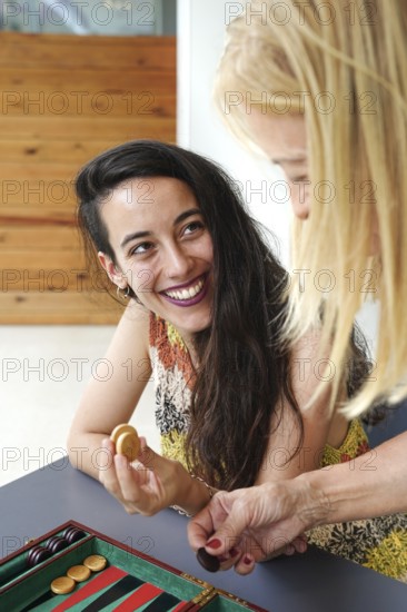Mother and daughter smile and enjoy a friendly game of backgammon in a relaxed setting They