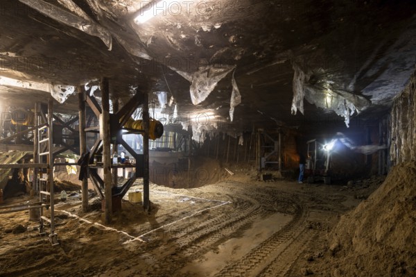 An expansive underground construction site featuring heavy machinery, scaffolding, and industrial