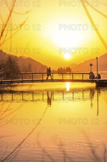 People on a bridge over a lake at sunset with intensive reflection, Großer Alpsee, Immenstadt im