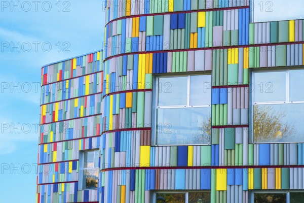 A stunning view of a modern building's curved facade adorned with multicolored panels. Bright