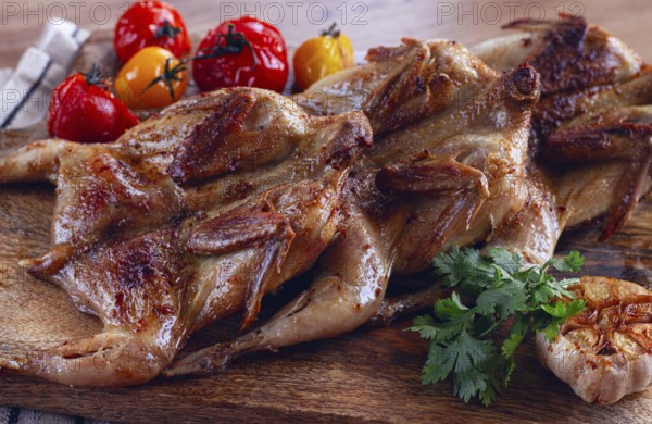 Grilled quail meat, on a wooden chopping board, tobacco, in the oven, with spices, homemade,
