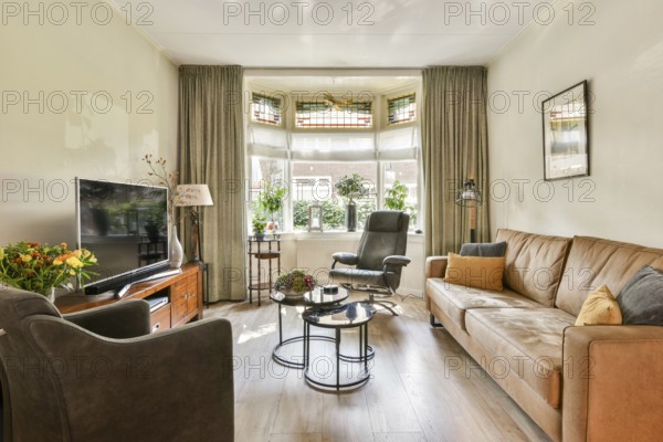 A beautifully arranged living room featuring comfortable furniture, a large window, plants, and