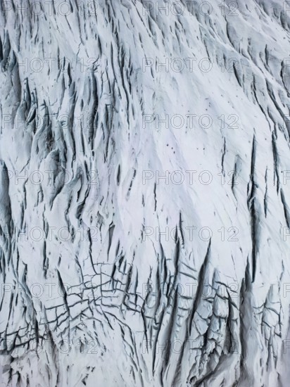 Aerial view of the Icelandic winter terrain, showcasing a dramatic, snow-covered landscape with