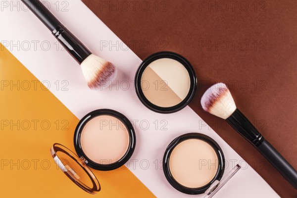 Flat lay of makeup brushes and face powders on a vibrant tricolor background. The contrasting