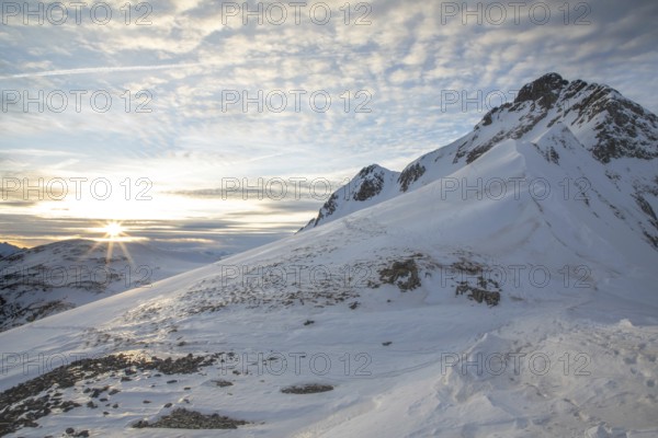 Scenic winter landscape with snow-covered mountains perfect for ski touring. The sunrise casts a