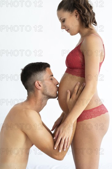A couple sharing an intimate moment, highlighting the beauty of pregnancy The man kisses the