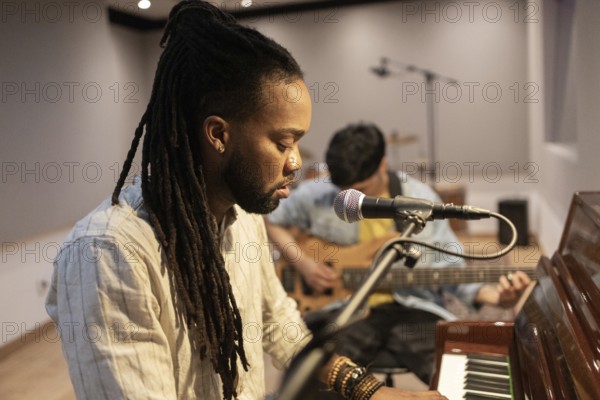 Two musicians immerse themselves in crafting music in a recording studio. One plays the piano while