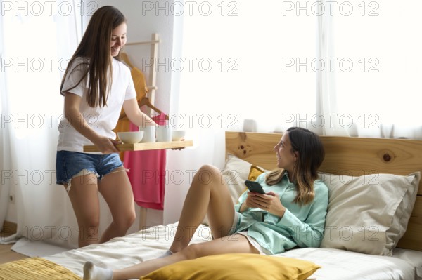 A joyful lesbian couple shares a tender moment in their sunlit bedroom One woman serves breakfast