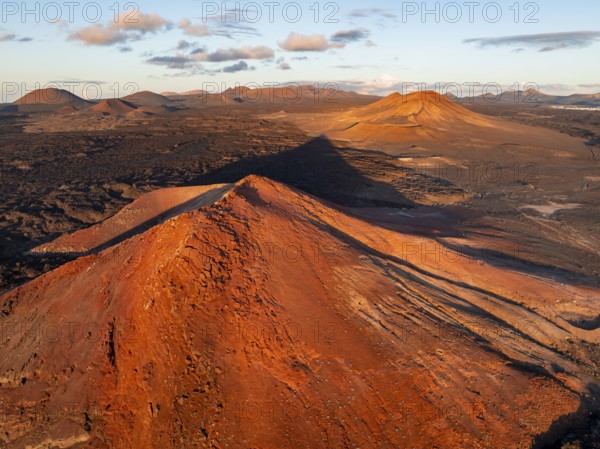 Picturesque volcanic landscape in evening light, red volcano Montaña Bermeja between lava fields,