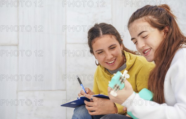 Two friends engage in a fun study session One plays a turquoise ukulele, while the other takes