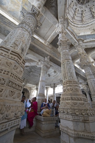 Indian woman praying between the white marble pillars in the Adinath temple in Ranakpur, Jain