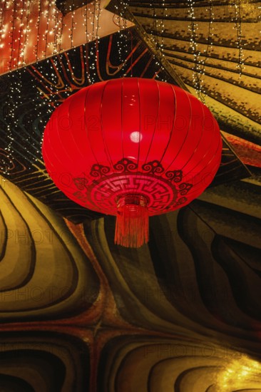 A vivid red lantern adorned with intricate patterns hangs in the festive atmosphere of a Taoist and