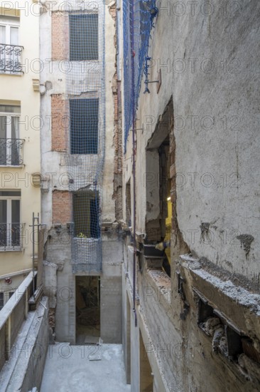 Urban building renovation site with exposed concrete and brick walls. Blue safety nets secure open