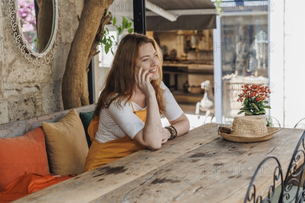 A mature woman, wearing an orange and yellow outfit, enjoys a phone call during her vacation in an