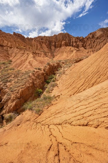 Eroded mountain landscape with sandstone cliffs, canyon with red and orange rock formations,