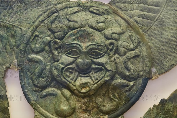 Winged gorgoneion acroterion, roof decoration from the Temple of Hera, an antique metallic face
