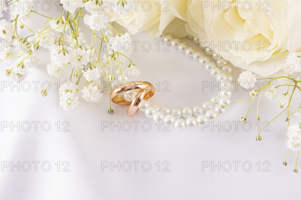 Elegant wedding rings lie nestled among delicate white roses and dainty baby's breath. The