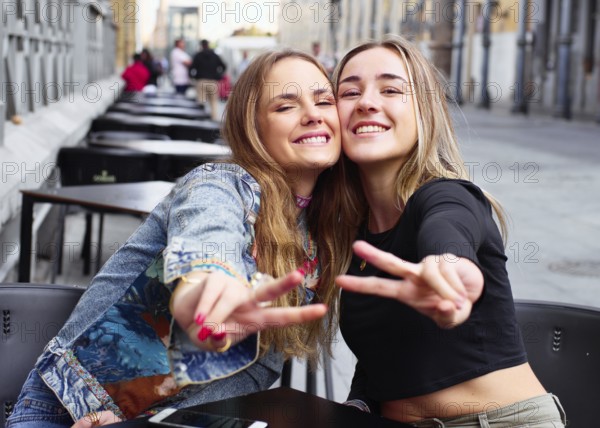 Two cheerful teenage friends enjoying time together outdoors, smiling and posing with peace signs.