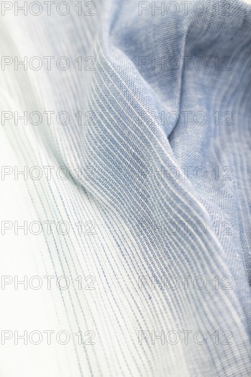 Fragment of blue and white linen tissue. Side view, textile blurred background and texture. Water