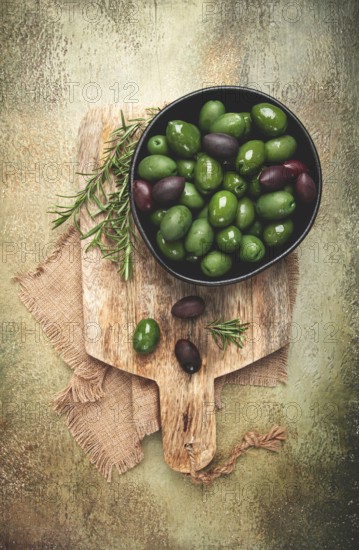 Chalkidiki olives, classic Greek green olives, in a bowl on a cutting board, top view, without