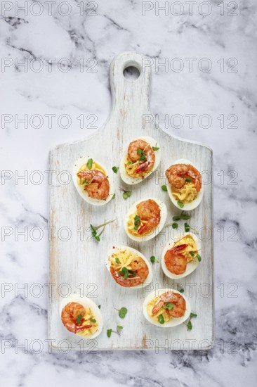Boiled eggs stuffed with yolk and seasoned with mayonnaise, stuffed eggs with shrimp, on a white