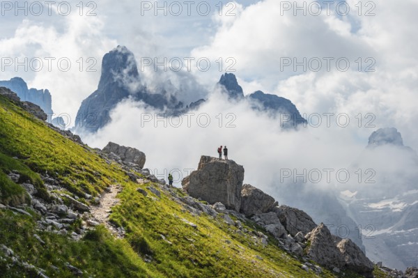 Alpine panorama, mountaineers on a large rock, fog and Torre Di Brentai and Cima Tosa, rocky
