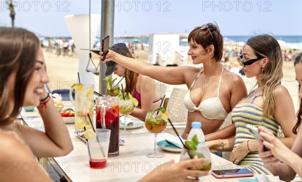 Friends gather around a beach bar, savoring colorful cocktails and laughing together. Some take