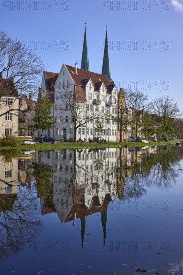 Historic house, towers of Lübeck Cathedral, trees, reflections on the surface of the water,