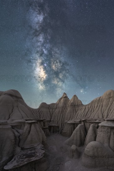 A breathtaking night sky filled with the Milky Way stretches above the unique, weathered rock