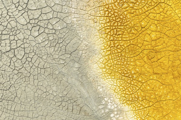 A close-up of cracked mud with striking multicolor patterns, featuring vivid yellow on one side and