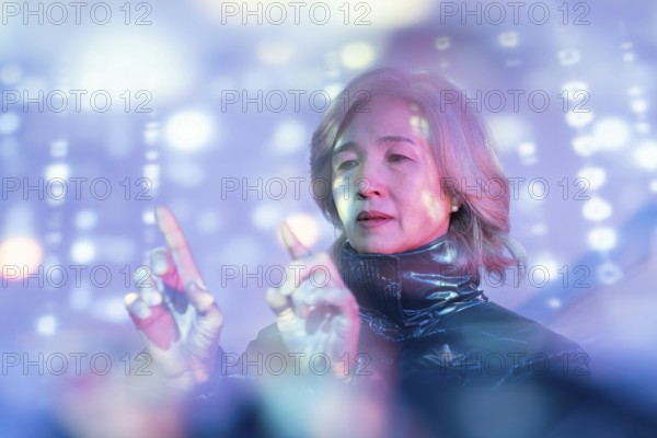 An elderly Asian woman explores the metaverse, engaging with virtual holographic displays. The