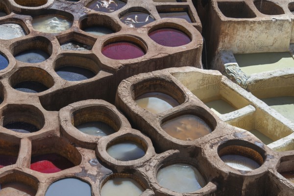 Aerial view of traditional leather tanning pits filled with vibrant dye baths in warm sunlight in