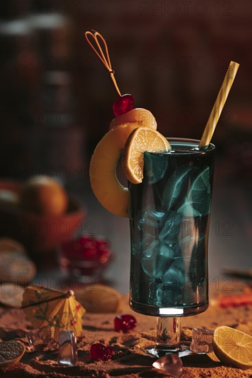 Cocktail in a glass with ice cube cubes, decorated with lime slices and cherries on a sandy