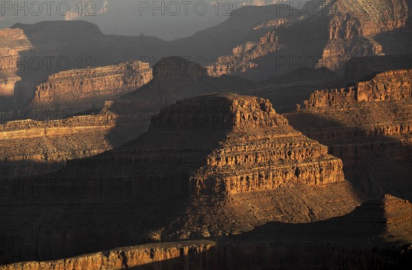 The Grand Canyon's rugged terrain is bathed in warm hues during sunset. This iconic USA landmark