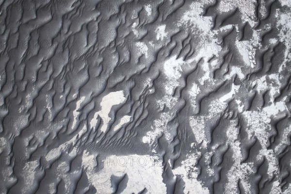 From above intricate patterns of black sand adorned with subtle white shades, creating a visually